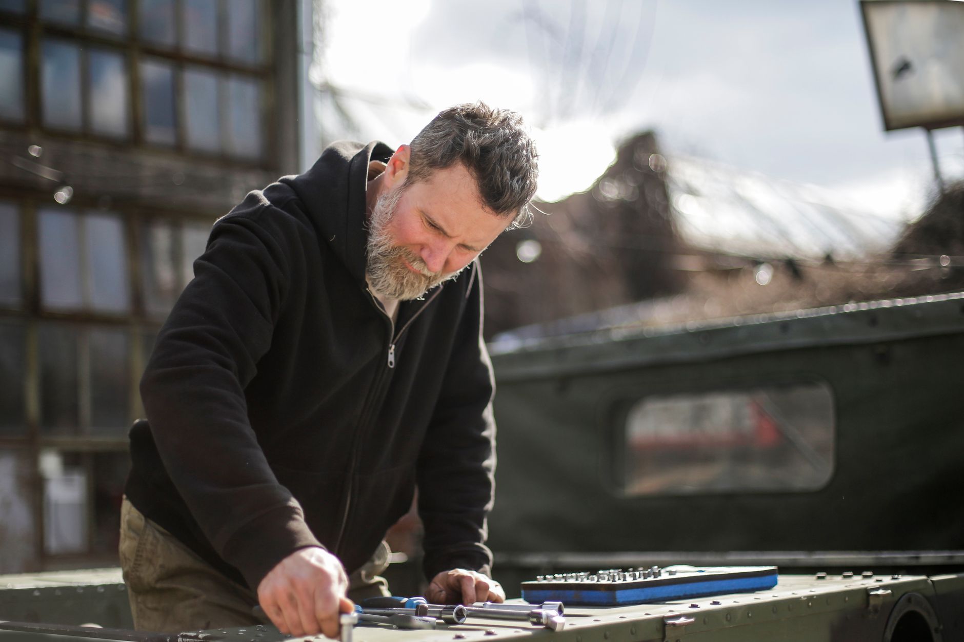 A professional roofer inspecting a roof in Randolph, Massachusetts, with a clear view of residential homes and autumn trees in the background.